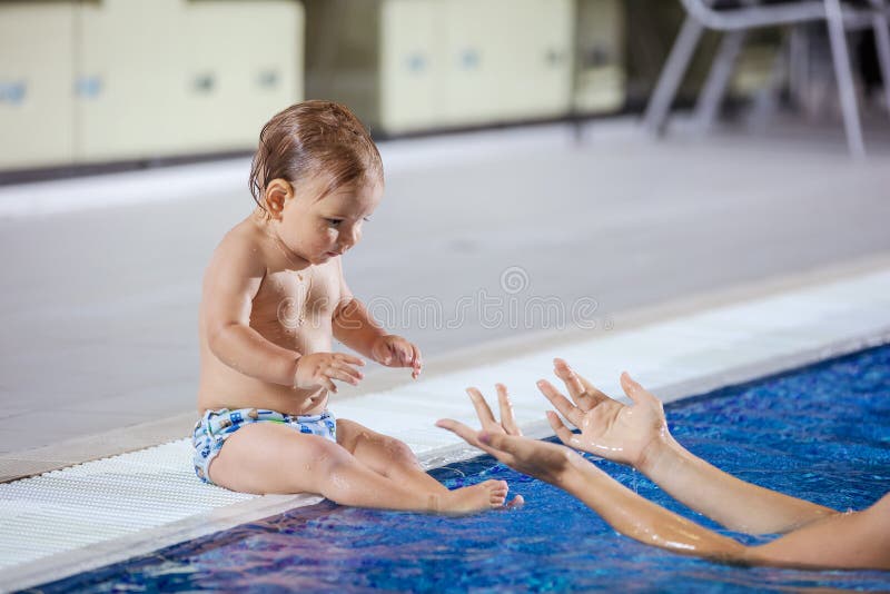 Young woman catching little son sitting poolside