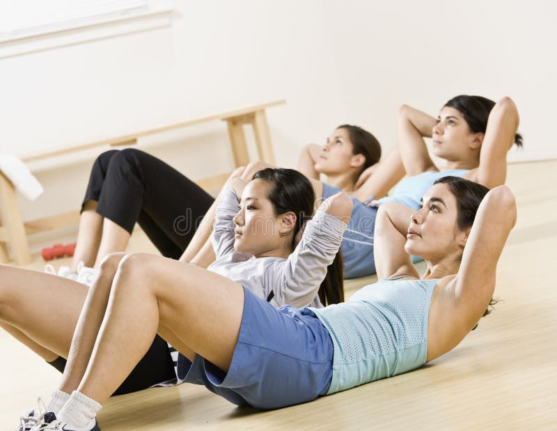 Young Women doing sit-ups in exercise class stock photos