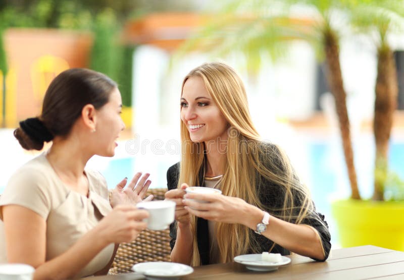 Young women drinking coffee in a cafe outdoors. Shallow depth of field