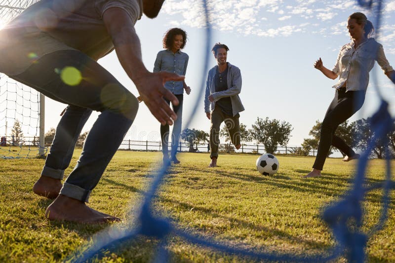 Young woman kicks football while playing with friends stock images Young woman kicks football while playing with friends stock images