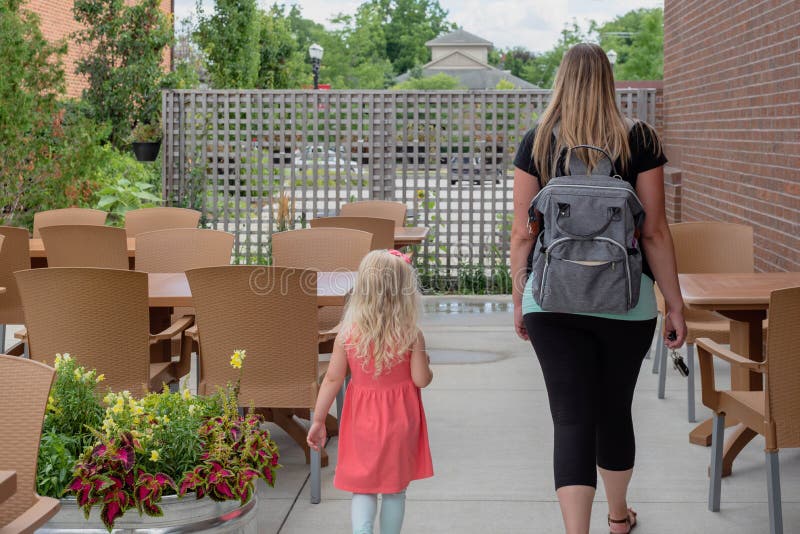 Young woman and little girl walking through an outdoor cafe royalty free stock photo Young woman and little girl walking through an outdoor cafe royalty free stock photo