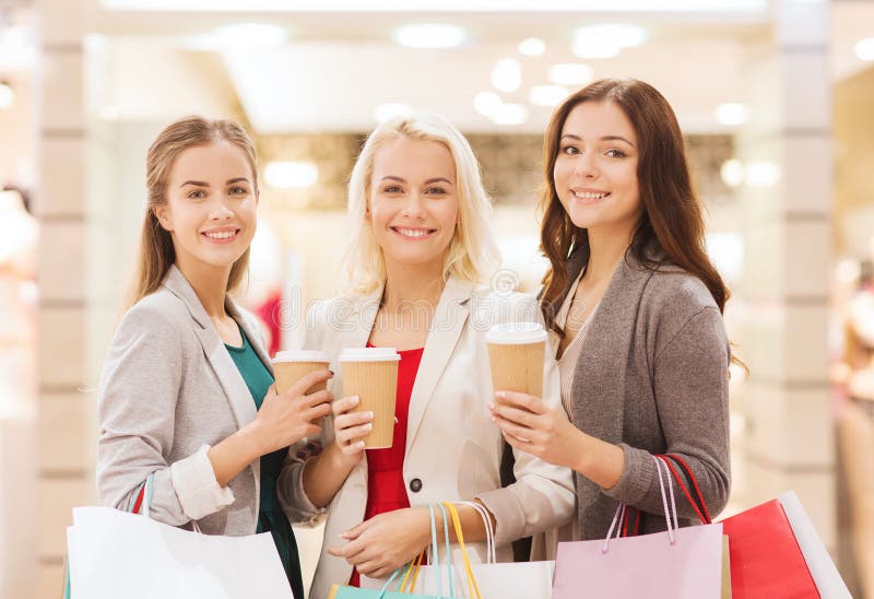 Young women with shopping bags and coffee in mall