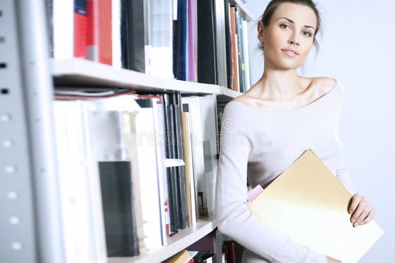 Young women stands near bookshelf