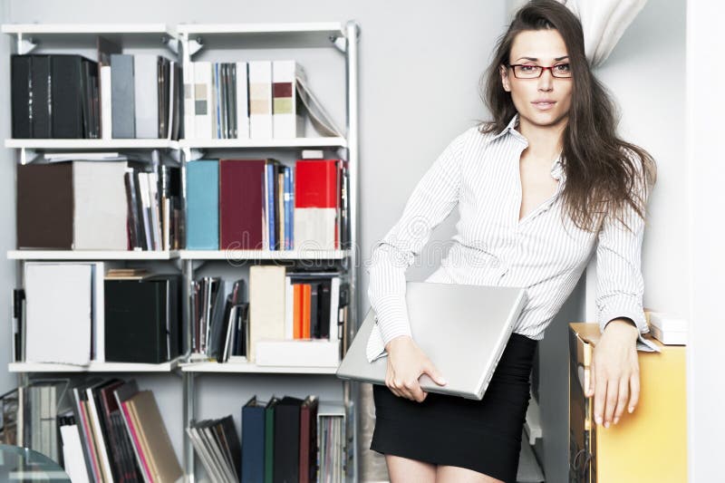 Young women stands near bookshelf