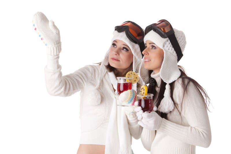 Beautiful young women in winter clothes and ski glasses drink mulled wine on a white background. Winter woolen clothes stock images, royalty-free photos and pictures