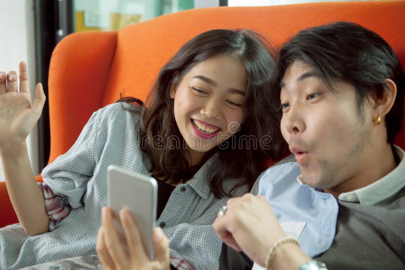 Younger asian man and woman happiness emotion when looking on sm