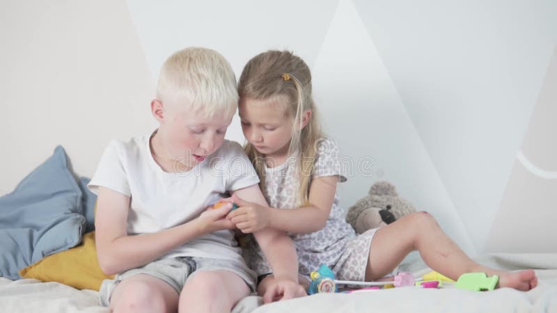 The Younger Sister Measures the Older Brother`s Temperature with a Toy Thermometer. Stock Footage - Video of medicine, measure: 187541168