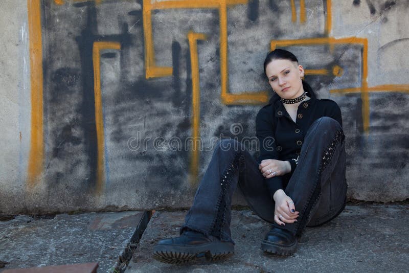 Young girl sitting in front of graffiti wall