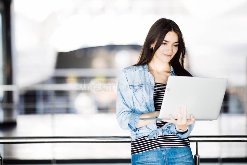 Youngwoman που λειτουργεί με το lap-top της στο κιγκλίδωμα στοκ εικόνες με δικαίωμα ελεύθερης χρήσης Youngwoman που λειτουργεί με το lap-top της στο κιγκλίδωμα στοκ εικόνες με δικαίωμα ελεύθερης χρήσης