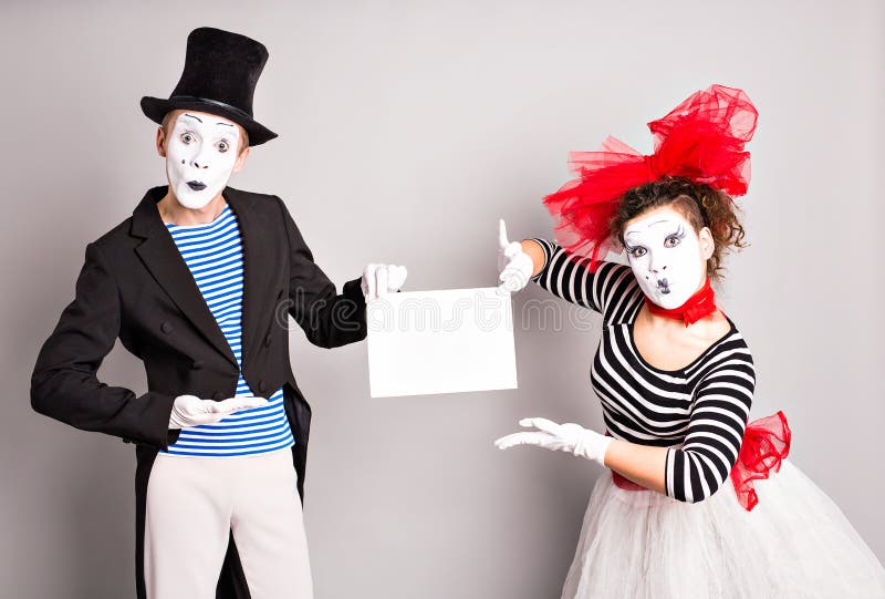 Your text here. Actors mimes holding empty blank board. Colorful studio portrait with gray background. April fools day. Brunette, color.