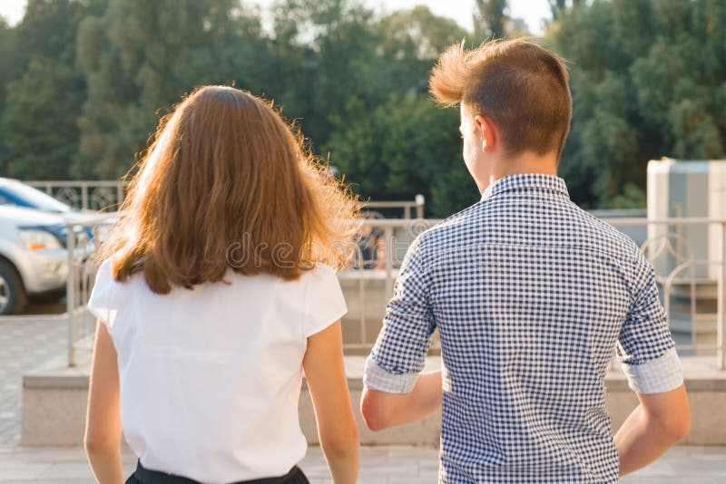 Youth boy and girl back view walking talking outdoor