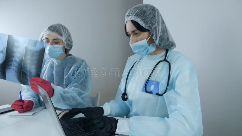 Yrkesforskare inom unga kvinnliga laboratorier som arbetar i modernt kliniskt laboratorium och diskuterar medicinska stock video
