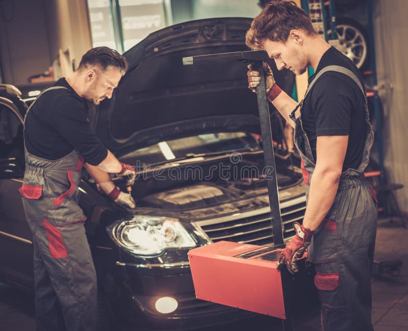 Yrkesmässiga bilmekaniker som kontrollerar billyktalampan av bilen i service för auto reparation royaltyfri foto Yrkesmässiga bilmekaniker som kontrollerar billyktalampan av bilen i service för auto reparation royaltyfri foto