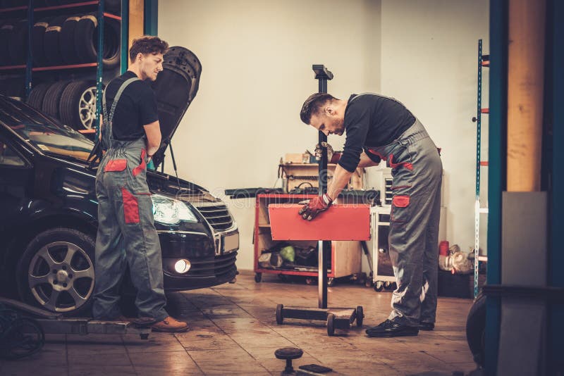Yrkesmässiga bilmekaniker som kontrollerar billyktalampan av bilen i service för auto reparation royaltyfria foton Yrkesmässiga bilmekaniker som kontrollerar billyktalampan av bilen i service för auto reparation royaltyfria foton
