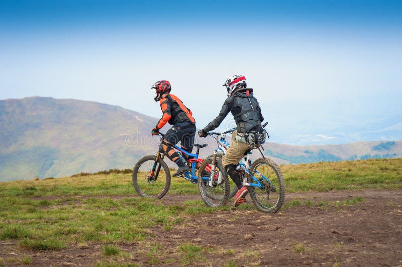 Yrkesmässiga cyklister som rider den sluttande mountainbiket på bergslingan royaltyfri bild Yrkesmässiga cyklister som rider den sluttande mountainbiket på bergslingan royaltyfri bild