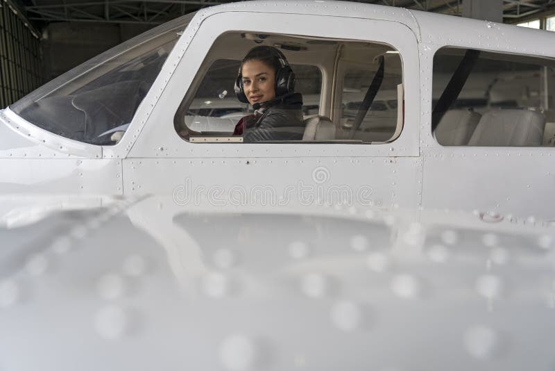 Yttre sikt av flygplan och den härliga kvinnapiloten With Headset i cockpiten arkivbild Yttre sikt av flygplan och den härliga kvinnapiloten With Headset i cockpiten arkivbild