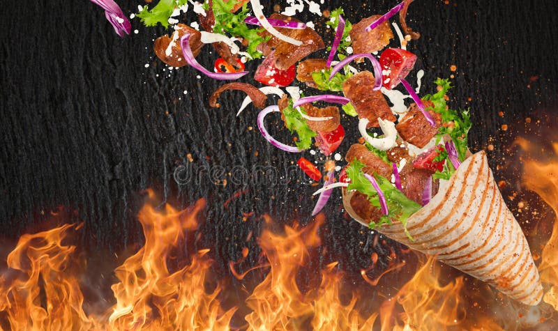 Yufka turc de chiche-kebab avec des ingrédients et des flammes de vol image stock Yufka turc de chiche-kebab avec des ingrédients et des flammes de vol image stock