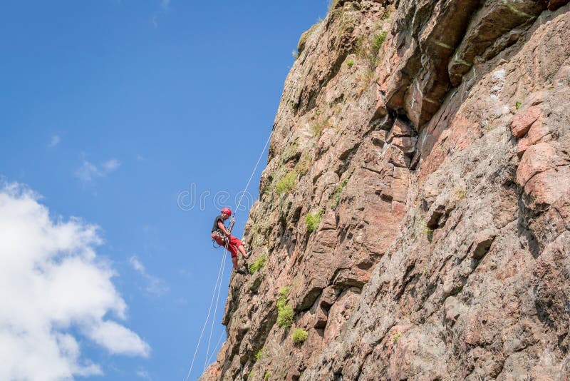 Yuzhnoukrainsk, Ukraine - 19 juin 2018 : Escalade Un jeune grimpeur monte une roche verticale de granit Sport extrême image libre de droits Yuzhnoukrainsk, Ukraine - 19 juin 2018 : Escalade Un jeune grimpeur monte une roche verticale de granit Sport extrême image libre de droits