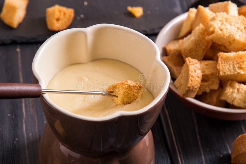 z bliska Tradycyjny francuski serowy fondue Crouton zamaczający w gorącego fondue z gruyere na wywodzącym się rozwidleniu fotografia royalty free z bliska Tradycyjny francuski serowy fondue Crouton zamaczający w gorącego fondue z gruyere na wywodzącym się rozwidleniu fotografia royalty free