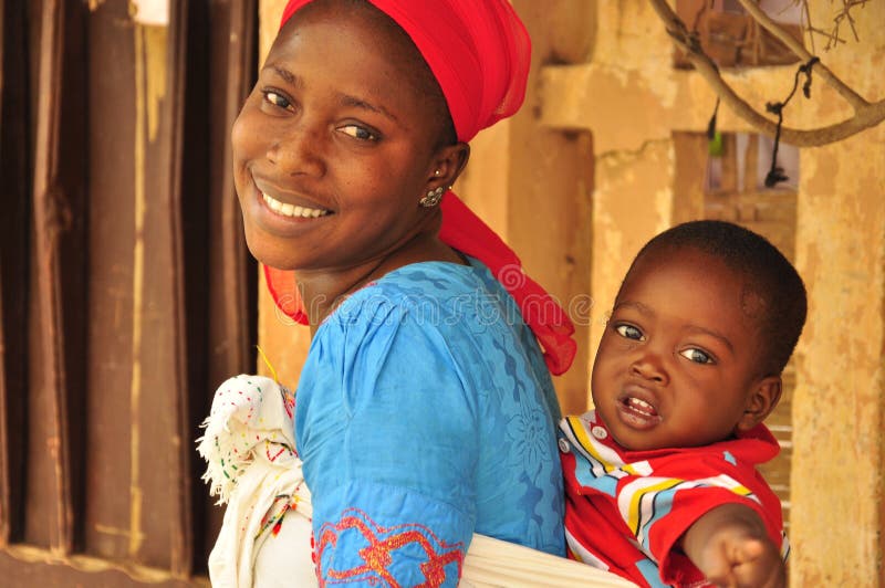 Beautiful african woman,smiling happy carrying little baby in Senegalese colorful dress. Senegal. Beautiful african woman,smiling happy carrying little baby in Senegalese colorful dress. Senegal