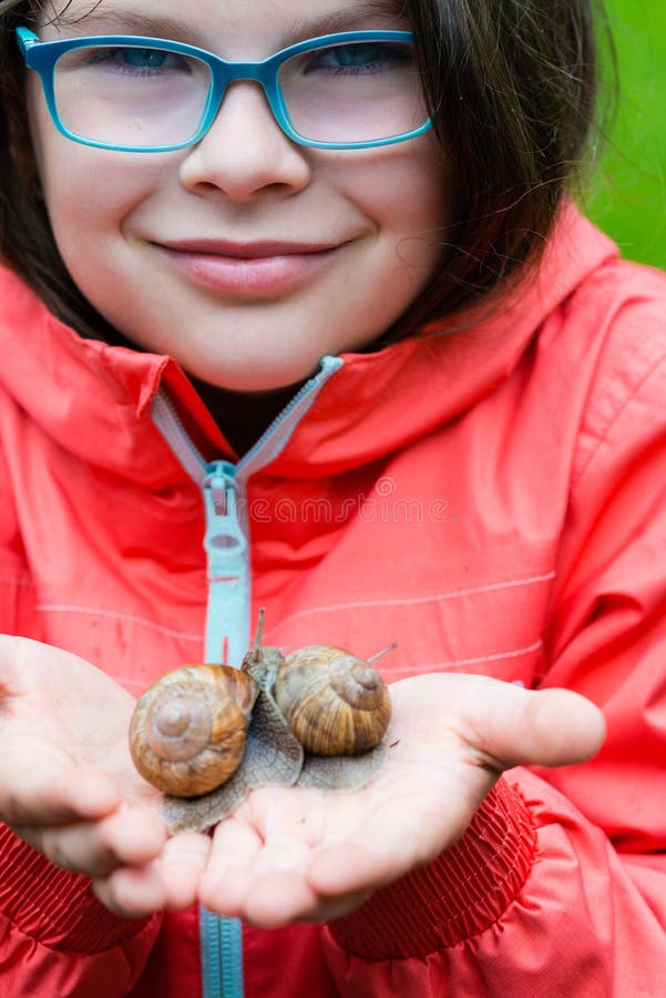 Zacht glimlachend de tuinslak van de meisjeholding stock foto's Zacht glimlachend de tuinslak van de meisjeholding stock foto's