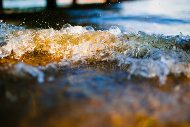 Soft wave reaching the pebble beach macro. Splashes of waves in sunlight. Soft wave reaching the pebble beach macro. Splashes of waves in sunlight