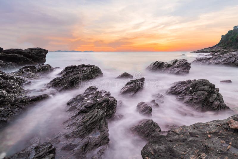 Soft waves of ocean in sunset with stones on the beach foreground at Khao Laem Ya Mu Ko Samet National Park Rayong, Thailand. Seascape long exposure shot. Soft waves of ocean in sunset with stones on the beach foreground at Khao Laem Ya Mu Ko Samet National Park Rayong, Thailand. Seascape long exposure shot