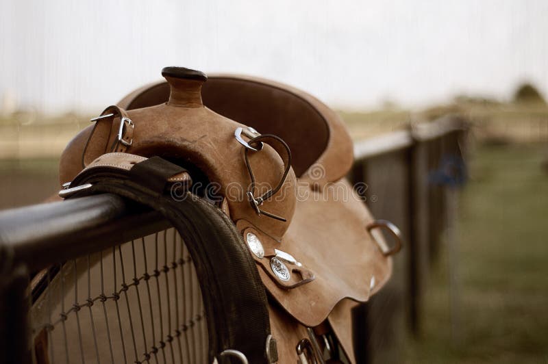 Brown leather saddle on a wooden and chicken wire fence. Brown leather saddle on a wooden and chicken wire fence.