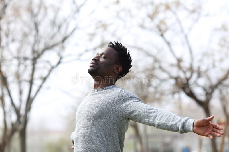 Zadowolony czarny człowiek oddychający świeżym powietrzem w parku