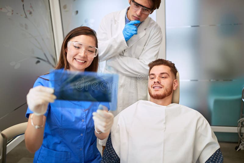 Zahnarzt mit Assistenzärztin, die die Röntgenuntersuchung der Zähne des Patienten aussieht lizenzfreies stockfoto