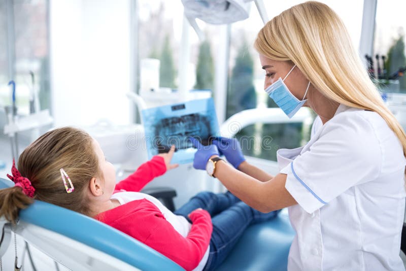 Zahnarzt und kleines Mädchen, die Röntgenstrahl von Zähnen betrachten lizenzfreies stockfoto Zahnarzt und kleines Mädchen, die Röntgenstrahl von Zähnen betrachten lizenzfreies stockfoto