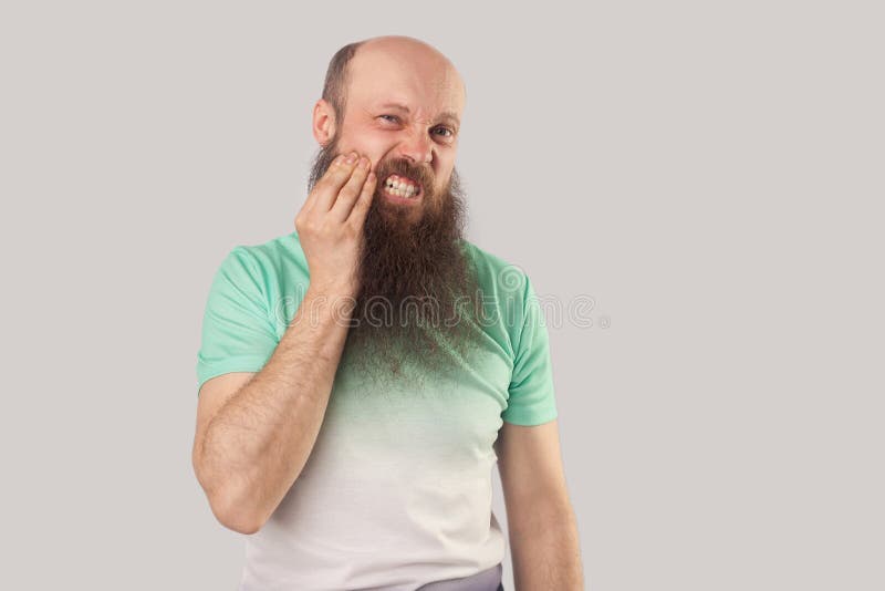 Zahnschmerzen Portrait eines kranken Glatzköchentiers mittleren Alters mit langem Bart in hellgrünem T-Shirt, das seine Wange ber