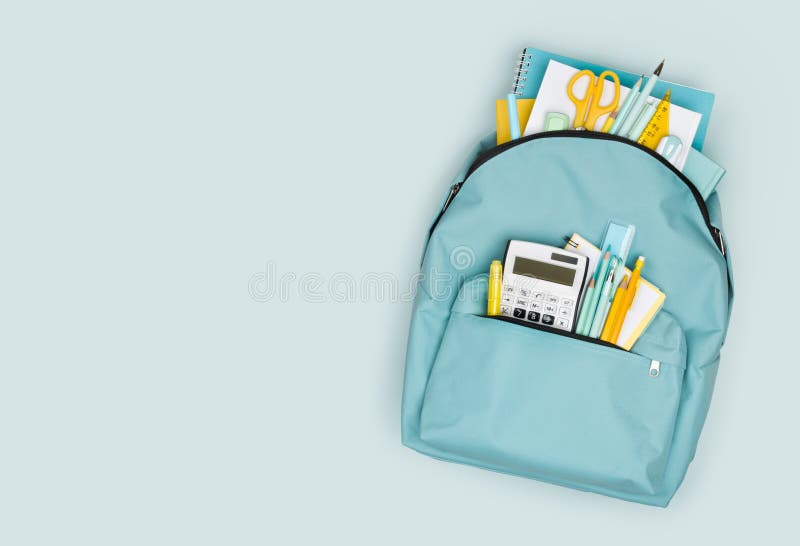 Zaino scolastico con diversi prodotti decorativi colorati su sfondo blu immagini stock