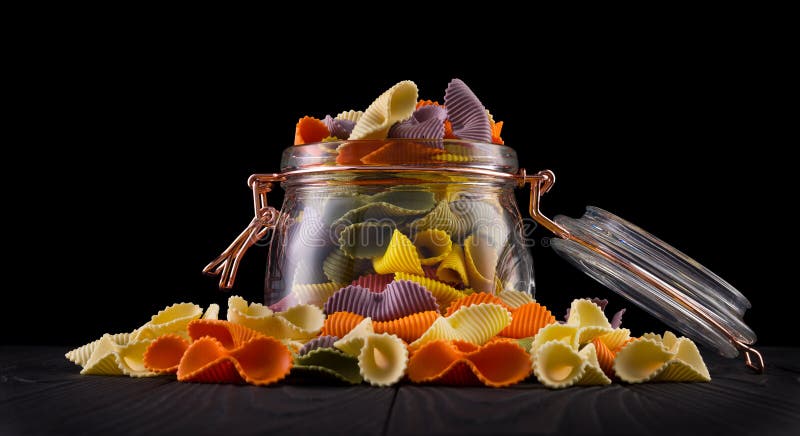 Zak van kleurrijke farfalle pasta op houten tafel geïsoleerd op zwarte achtergrond royalty-vrije stock foto Zak van kleurrijke farfalle pasta op houten tafel geïsoleerd op zwarte achtergrond royalty-vrije stock foto