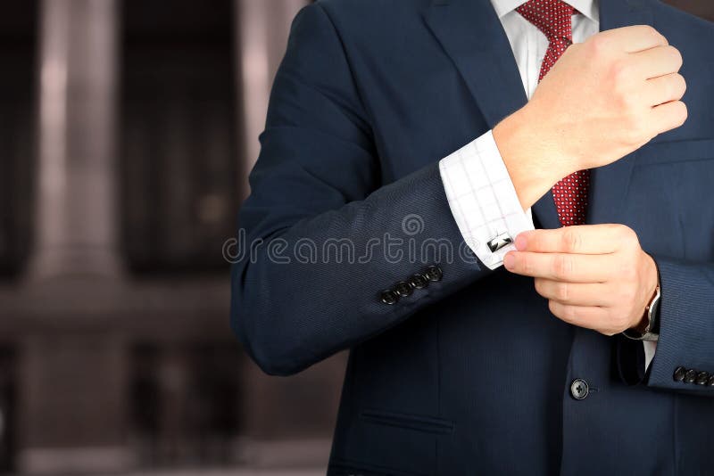 Zaken en bureauconcept - elegante jonge manier bedrijfsmens in blauw/marinekostuum het raken bij zijn cufflinks stock afbeeldingen Zaken en bureauconcept - elegante jonge manier bedrijfsmens in blauw/marinekostuum het raken bij zijn cufflinks stock afbeeldingen