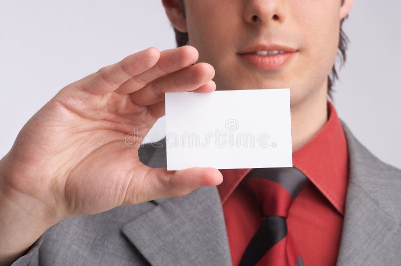 ambitious businessman in his grey suit holds a business-card in a hand, introducing and presenting his company, introduction - formal presentation of a smart person before the interview or meeting. ambitious businessman in his grey suit holds a business-card in a hand, introducing and presenting his company, introduction - formal presentation of a smart person before the interview or meeting
