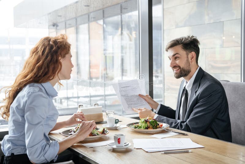 Zakenlui die bedrijfslunch hebben bij restaurantzitting dichtbij venster die salade eten die vrolijk project bespreken royalty-vrije stock foto's Zakenlui die bedrijfslunch hebben bij restaurantzitting dichtbij venster die salade eten die vrolijk project bespreken royalty-vrije stock foto's