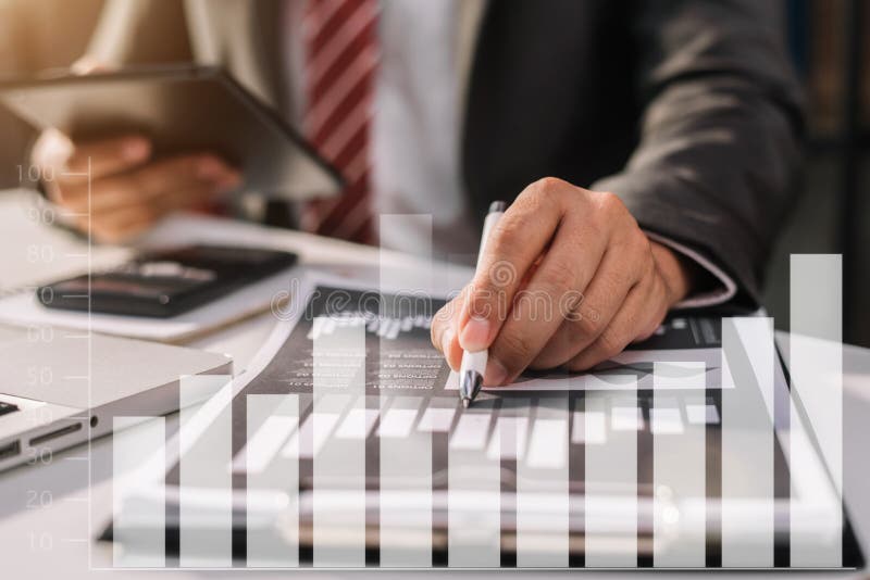 Male businessman using a tablet and computer to analysis graph company financial in office. Male businessman using a tablet and computer to analysis graph company financial in office.