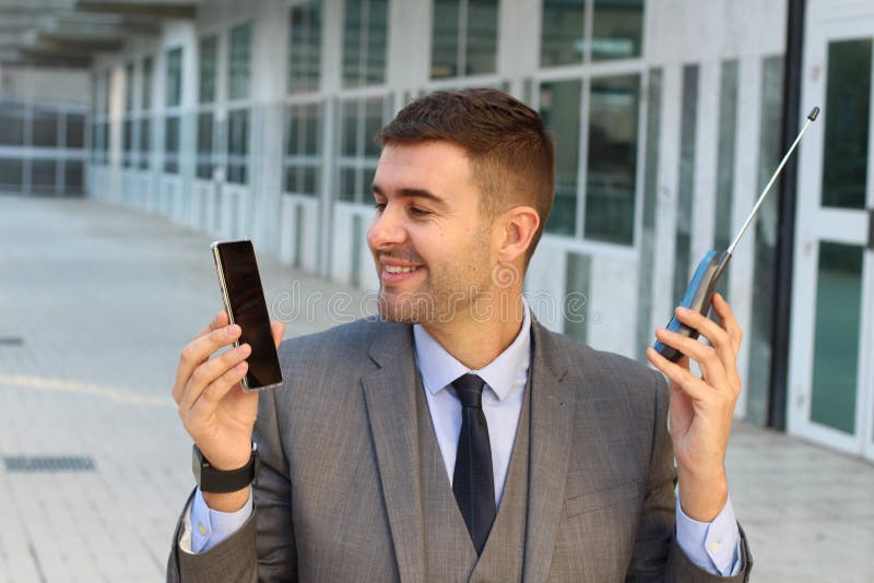 Zakenman die nieuwe en oude telefoon vergelijken royalty-vrije stock afbeelding Zakenman die nieuwe en oude telefoon vergelijken royalty-vrije stock afbeelding