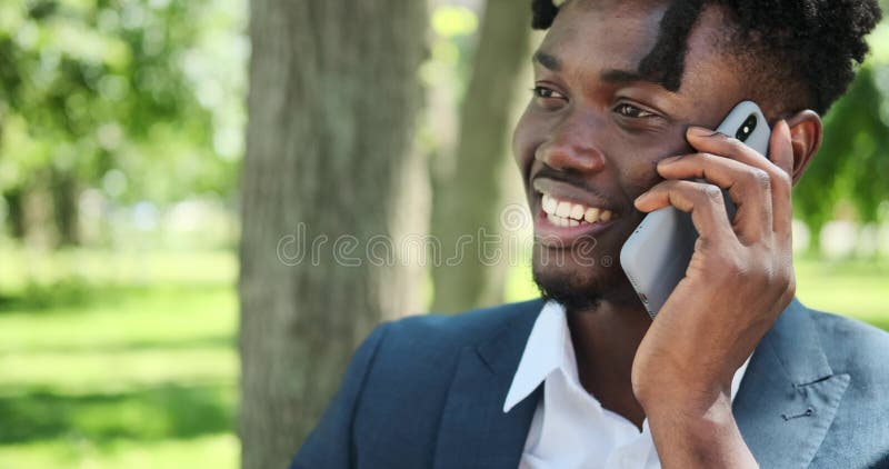 Zakenman die op het stadspark met mobiele telefoon praat