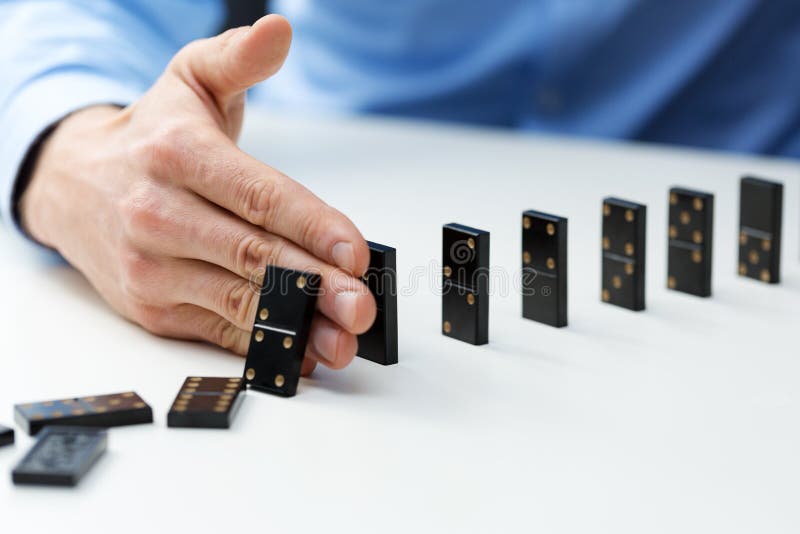 closeup of businessman stopping domino effect - business problem solving concept. closeup of businessman stopping domino effect - business problem solving concept