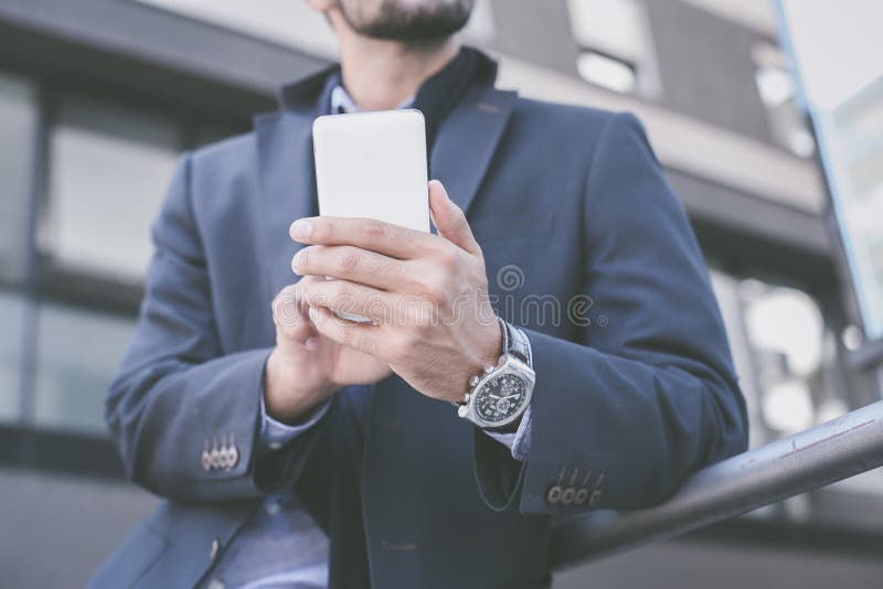 Zakenman die zich op stadsstraat bevinden en slimme telefoon houden stock afbeelding Zakenman die zich op stadsstraat bevinden en slimme telefoon houden stock afbeelding