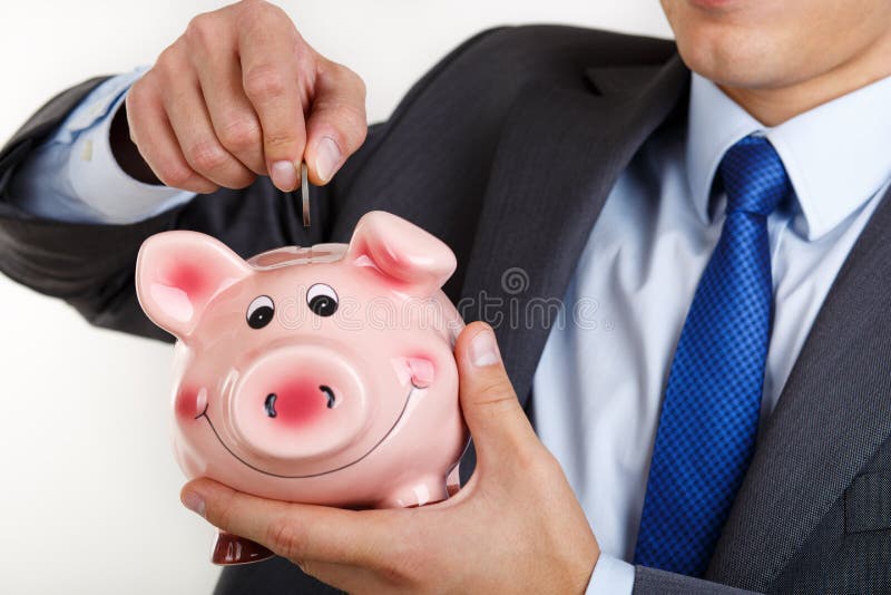 Zakenman in kostuum en band die de muntstukken van het speldgeld zetten in roze pi stock fotografie Zakenman in kostuum en band die de muntstukken van het speldgeld zetten in roze pi stock fotografie