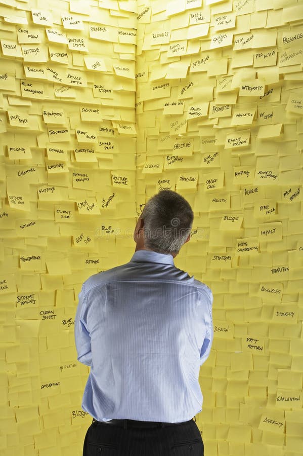 Zakenman Looking At Wall in Kleverige Nota's wordt geregeld die stock afbeeldingen Zakenman Looking At Wall in Kleverige Nota's wordt geregeld die stock afbeeldingen