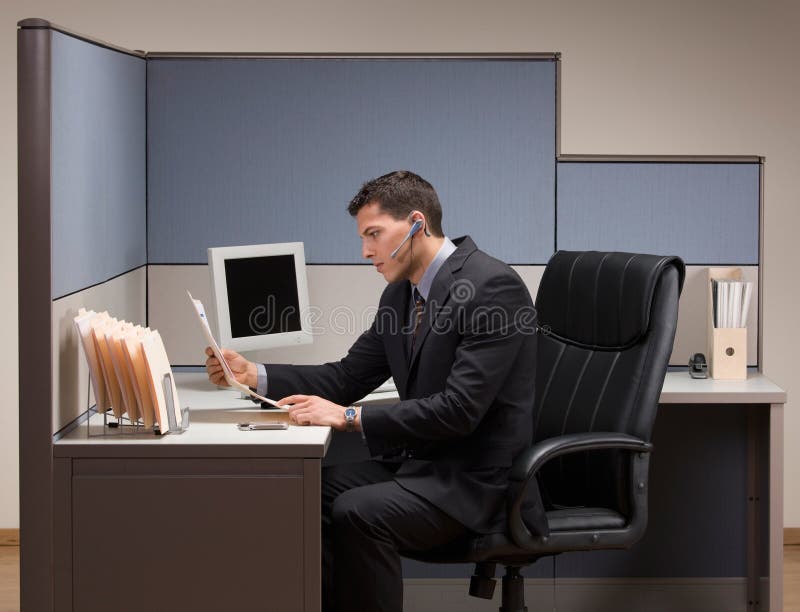 Zakenman met hoofdtelefoon die bij bureau in cubicl werkt royalty-vrije stock foto's Zakenman met hoofdtelefoon die bij bureau in cubicl werkt royalty-vrije stock foto's