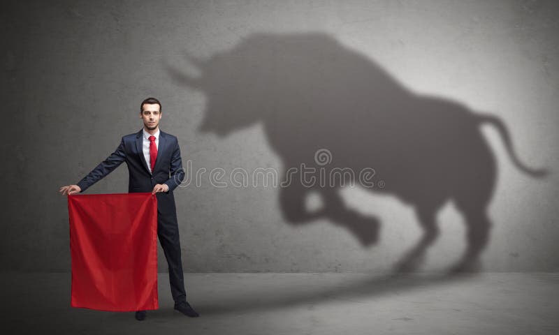 Businessman standing with red cloth in his hand and big bull shadow on the walln. Businessman standing with red cloth in his hand and big bull shadow on the walln