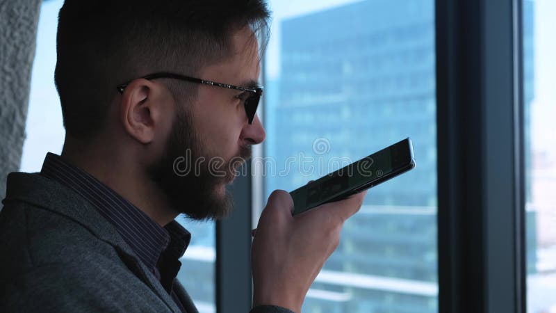 Zakenman Smiles After Sending een Stembericht Modieuze moderne jonge mens met een baardzakenman die een stem schrijven