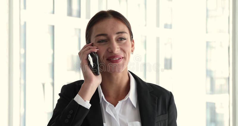 Zakenvrouw die op kantoor is en een mobiele telefoon houdt , geniet van aangenaam gesprek