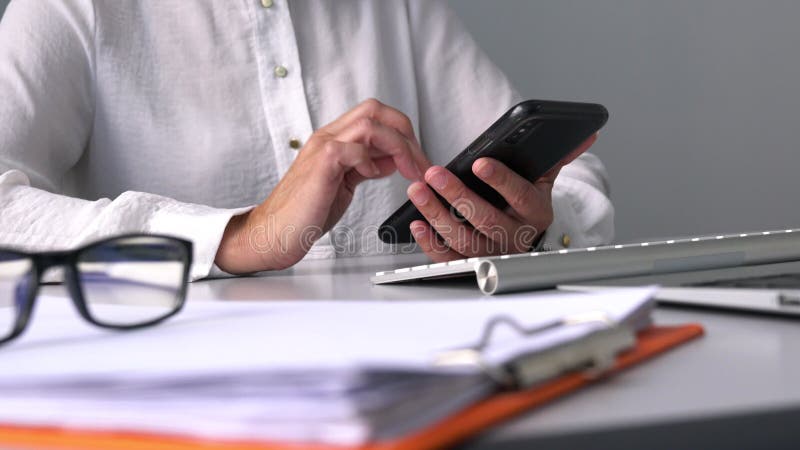 Zakenvrouw die sms't op haar mobiele telefoon aan de werktafel.