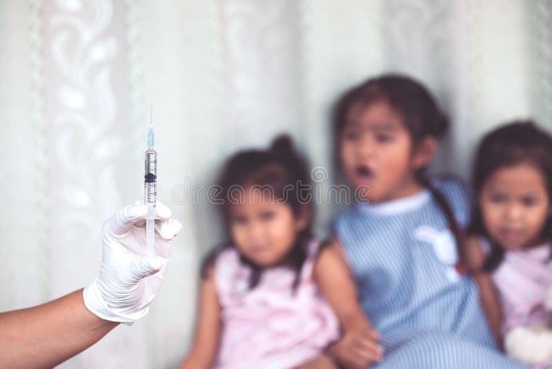 Zakończenia up lekarki ręki mienia strzykawka z dziecko dziewczyny strachem fotografia stock Zakończenia up lekarki ręki mienia strzykawka z dziecko dziewczyny strachem fotografia stock
